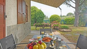 An outdoor dining area with a table set for breakfast, including fruits, croissants, and beverages. - Villa Tamara in San Felice del Benaco (San Felice del Benaco)
