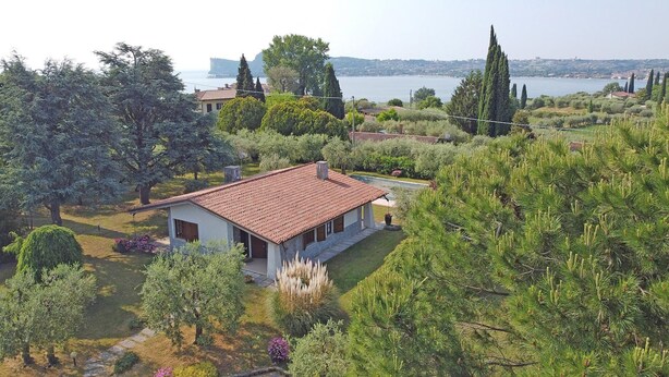 A house with a tiled roof, surrounded by trees and a view of a body of water. - Villa Tamara in San Felice del Benaco (San Felice del Benaco)