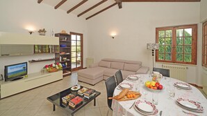 A dining area with a table set for four, surrounded by a sofa and a bookshelf. - Villa Tamara in San Felice del Benaco (San Felice del Benaco)
