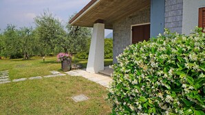A house with a stone facade, a wooden porch, and a well-maintained garden with flowering plants. - Villa Tamara in San Felice del Benaco (San Felice del Benaco)
