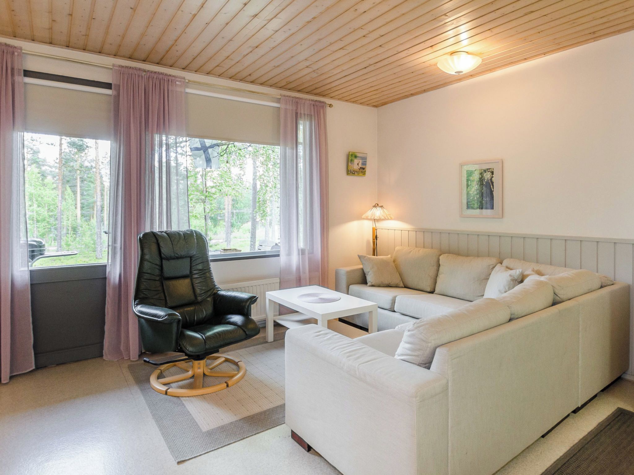 A cozy living room with a leather chair, a white sofa, a small table, and a lamp.