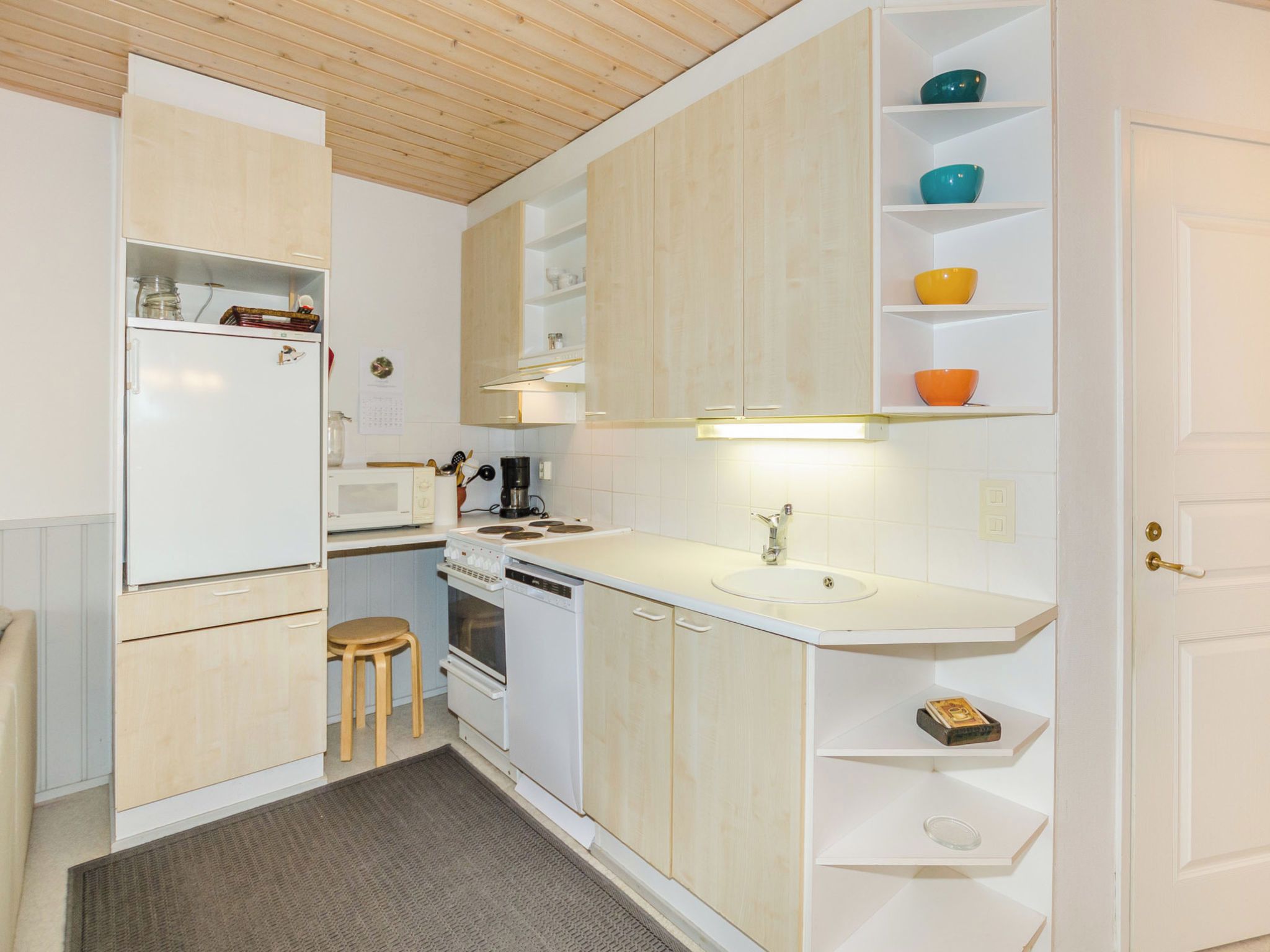 Eine kleine Küche mit Kühlschrank, Mikrowelle, Herd und Spüle.