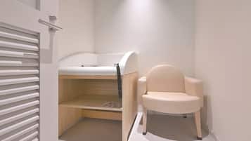 Ein kleines Zimmer mit Etagenbett und einem Sessel.