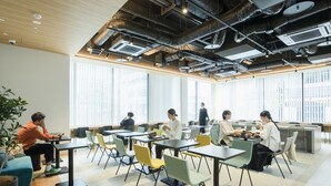 A modern office space with multiple tables and chairs, large windows, and exposed ductwork on the ceiling. - Prince Smart Inn Hakata (Fukuoka)