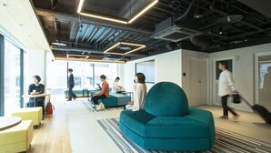 A modern office space with a teal sofa, yellow chairs, and a mix of natural and artificial lighting. - Prince Smart Inn Hakata (Fukuoka)