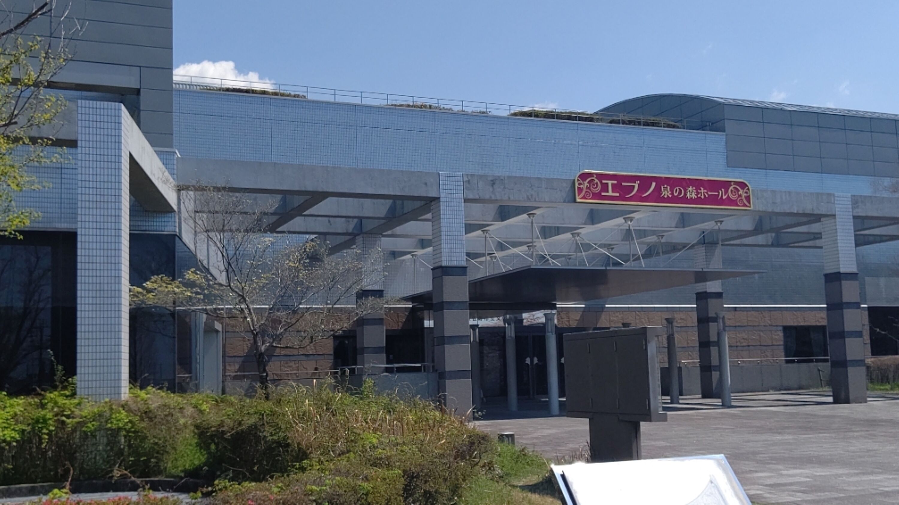 A modern building with a large entrance and a sign in Japanese.