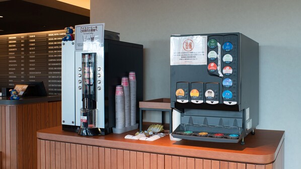 Una máquina de café con diversas opciones de bebidas y un panel con nombres de hoteles y horarios.