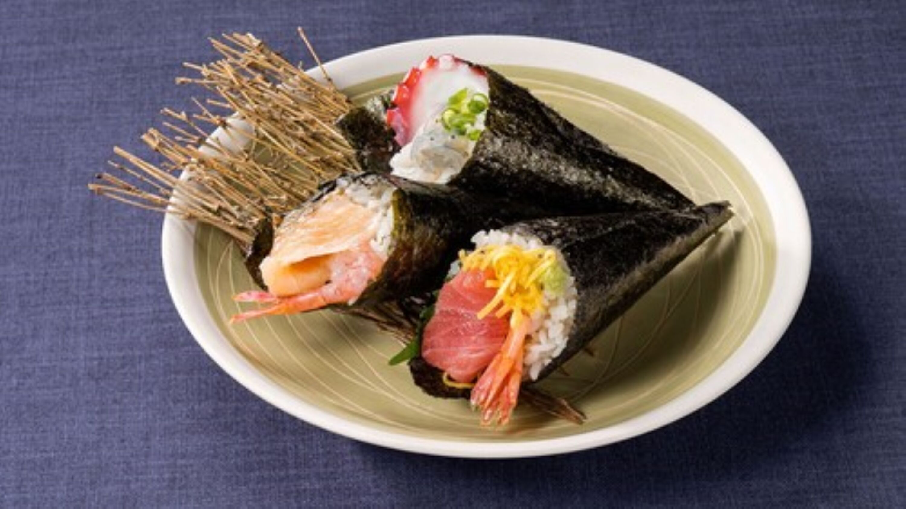 A plate of sushi with various toppings and a side of pickled ginger.