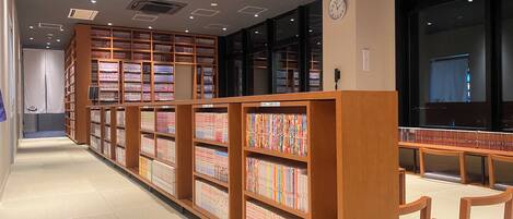 A library with wooden bookshelves and a clock on the wall.