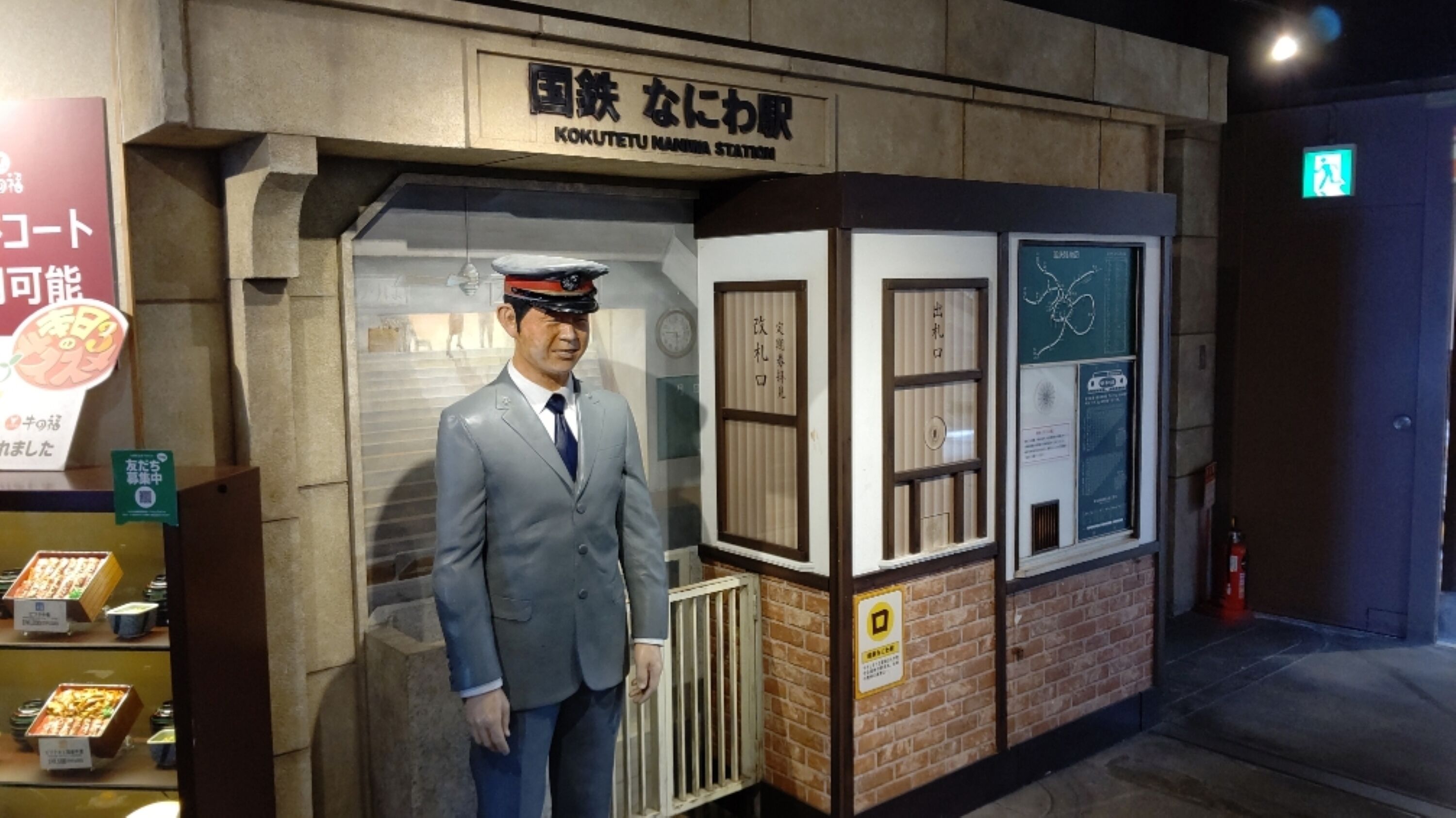 Une maquette représentant un homme en costume et chapeau, debout devant un bâtiment portant l'inscription « Kokutetu Marine Station ».