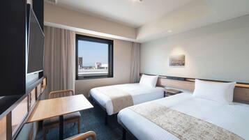 A hotel room with two beds, a desk, a chair, a TV, and a window with a city view.