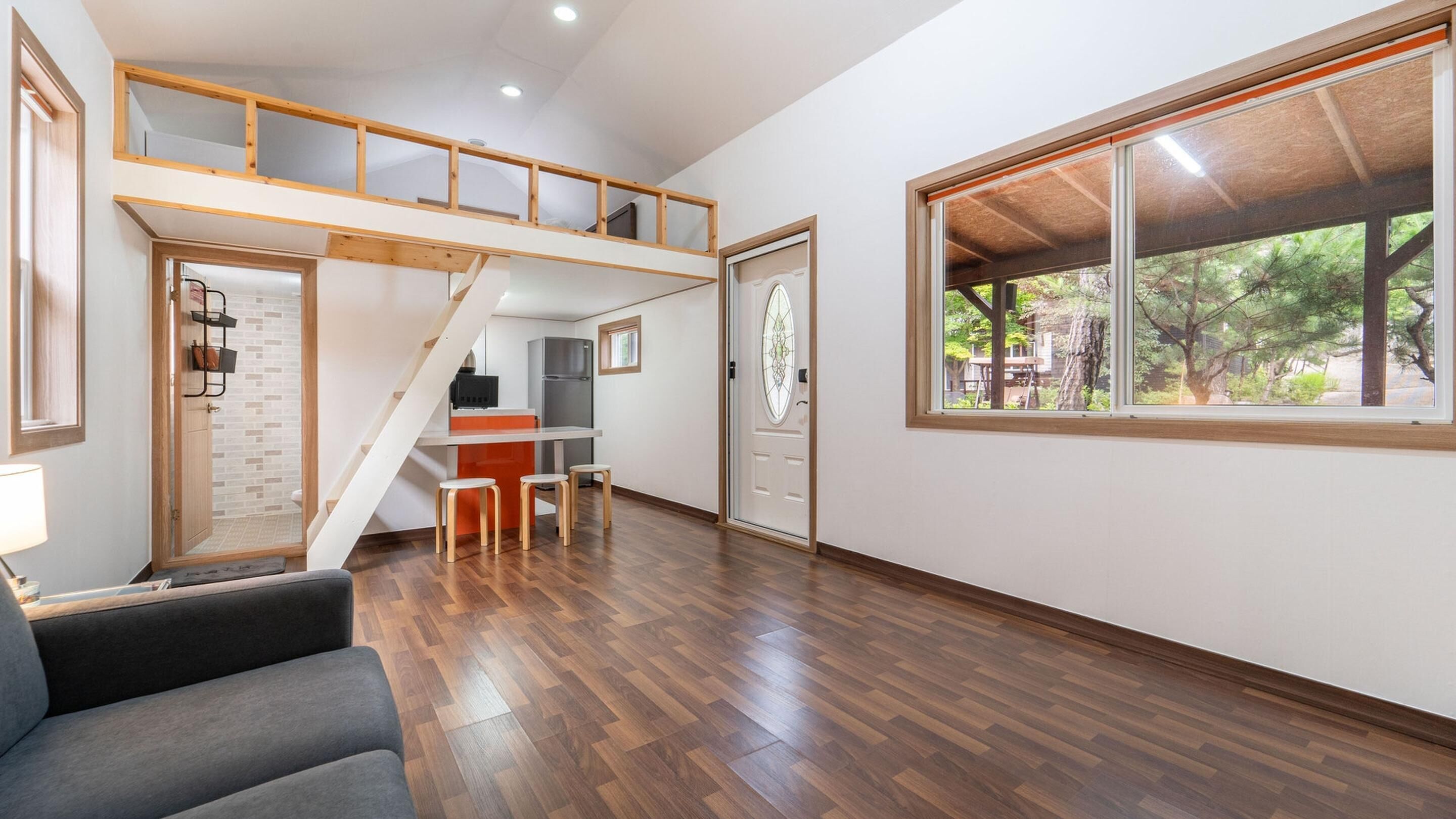 A modern interior with a loft bedroom, a kitchen, and a dining area.