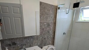 Une salle de bain moderne avec un meuble-lavabo blanc, des toilettes et une douche à parois de verre.