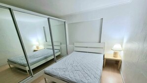 Une chambre à coucher comprenant un lit, une table de chevet, un miroir et une étagère fixée au mur.