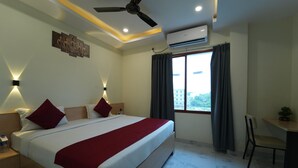 Une chambre d’hôtel avec un lit, des tables de chevet, un bureau et une chaise.