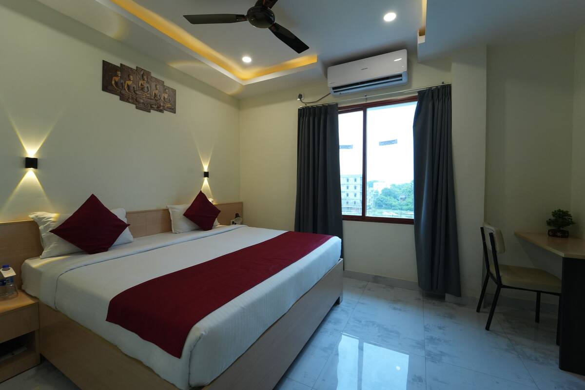 Une chambre d’hôtel avec un lit, des tables de chevet, un bureau et une chaise.