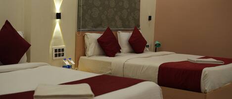 A hotel room with two beds, each with red and white bedding, and a large patterned curtain.