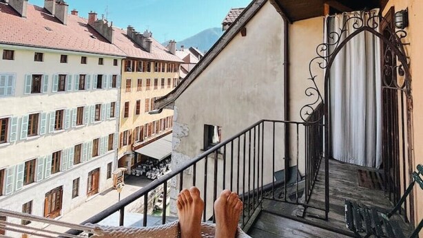 A balcony with a hammock, a staircase, and a view of buildings. - Loft in heart of Annecy with balcony over river (Annecy)