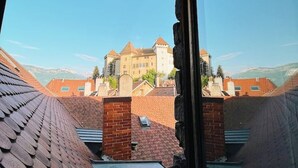 A view from a window overlooking a castle-like building with multiple towers and a large central structure. - Loft in heart of Annecy with balcony over river (Annecy)