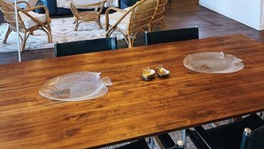 A cozy living area with a wooden dining table, wicker chairs, and a sofa with cushions. - Loft in heart of Annecy with balcony over river (Annecy)