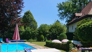 En baghave med swimmingpool, havemøbler og et bord.