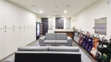 A reception area with a grey sofa, a reception desk, and a row of golf bags.