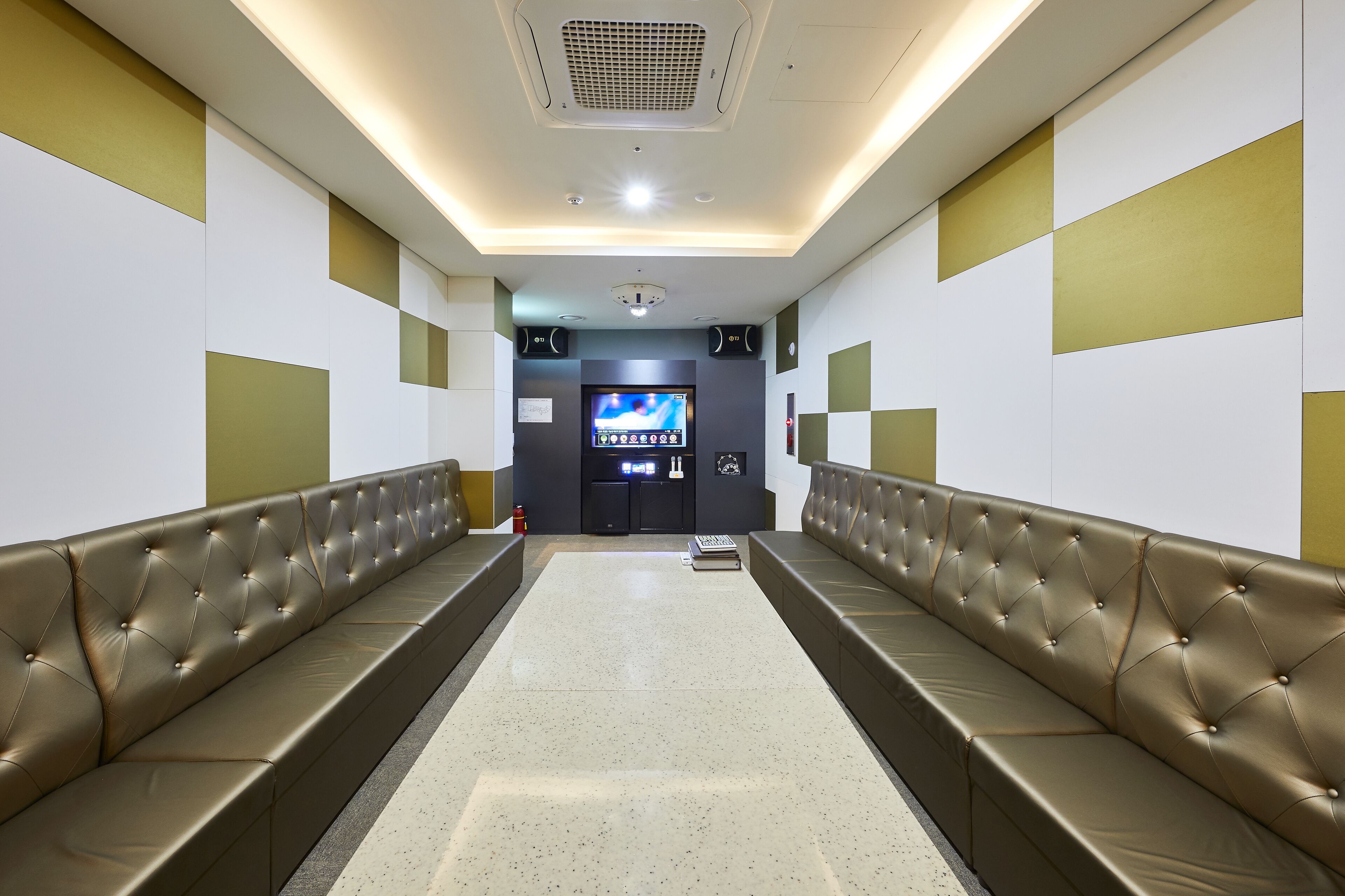 A modern waiting area with a long bench, a flat-screen TV, and a vending machine.