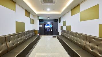 A modern waiting area with a long bench, a flat-screen TV, and a vending machine.