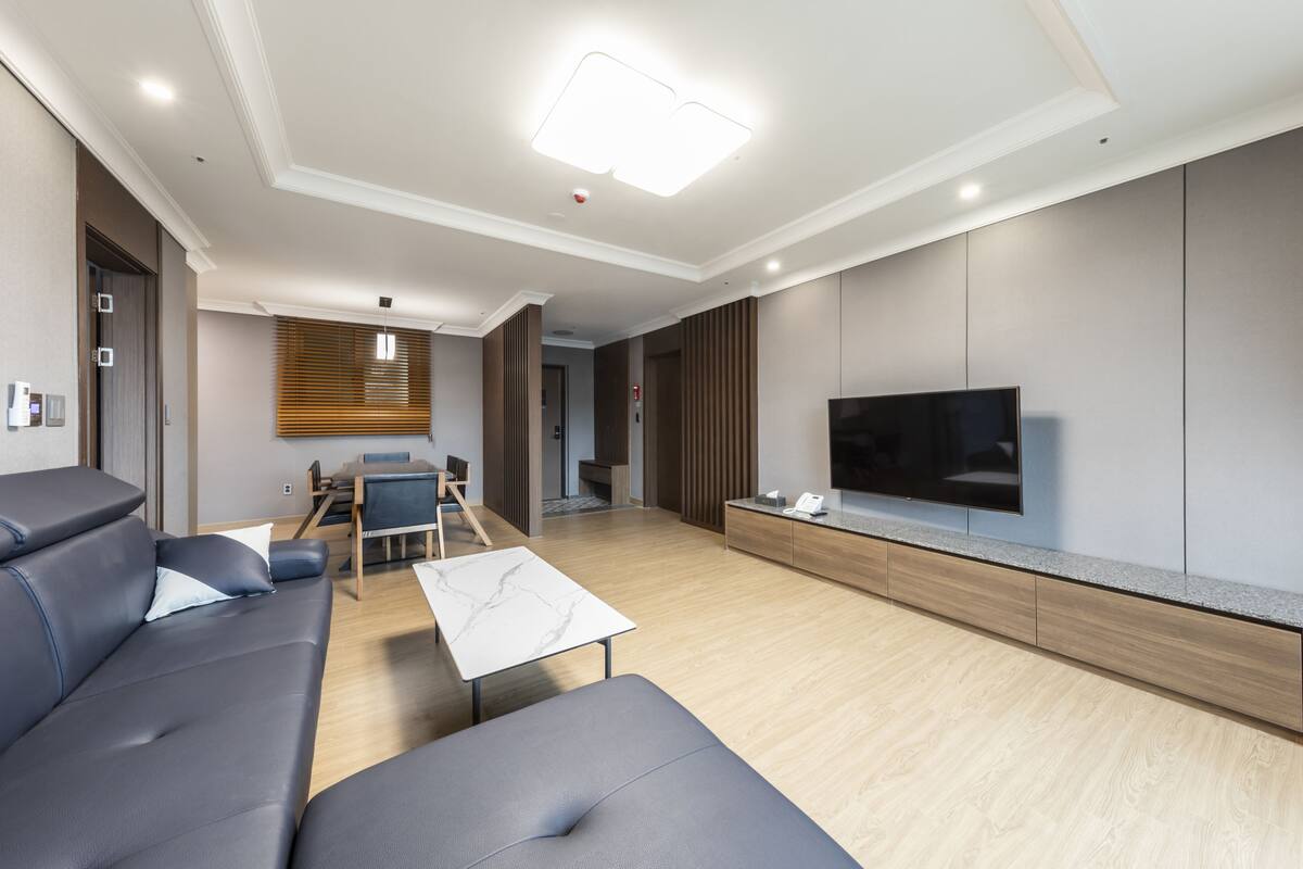 A modern living room with a sofa, a coffee table, and a flat-screen TV mounted on the wall.