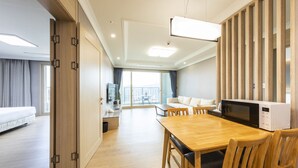 Una habitación de hotel moderna con una mesa de comedor de madera, sillas, un microondas y un sofá.