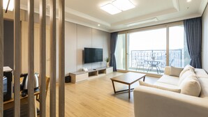 Una sala moderna con sofá, una mesa de centro, televisor y un balcón con vistas.