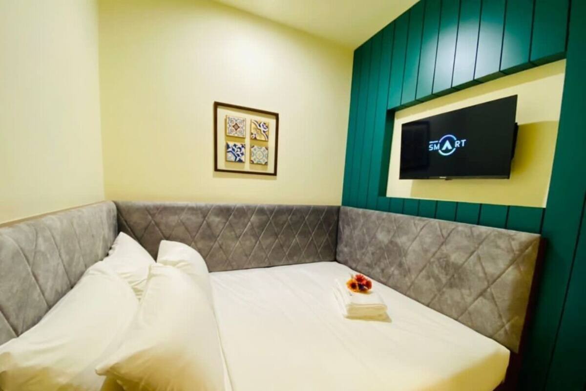 A hotel room with a bed, a TV mounted on the wall, and a framed artwork above the bed.