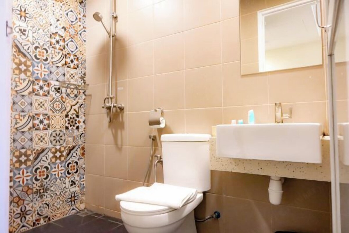 Une salle de bain avec un mur recouvert de carreaux à motifs, des toilettes, un lavabo et un miroir.