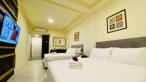 Habitación de hotel con dos camas, un televisor y decoración en la pared.