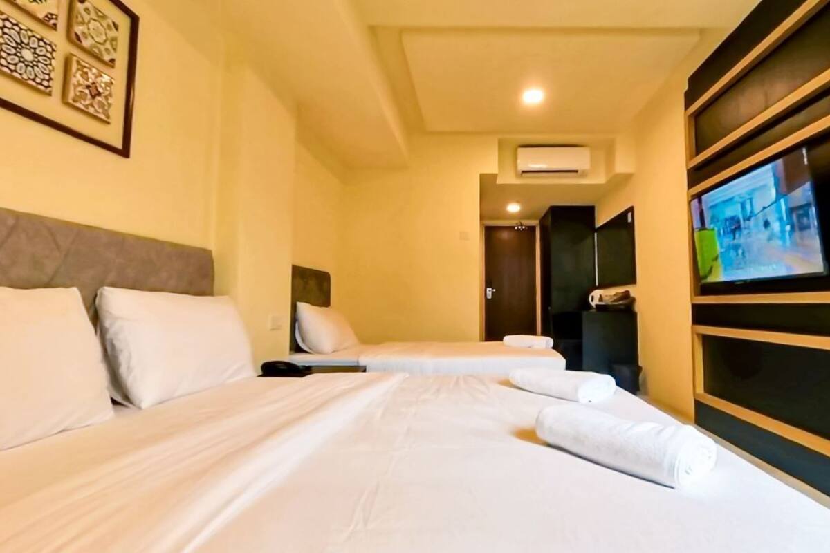 A hotel room with a large bed, a TV mounted on the wall, and a door leading to a bathroom.
