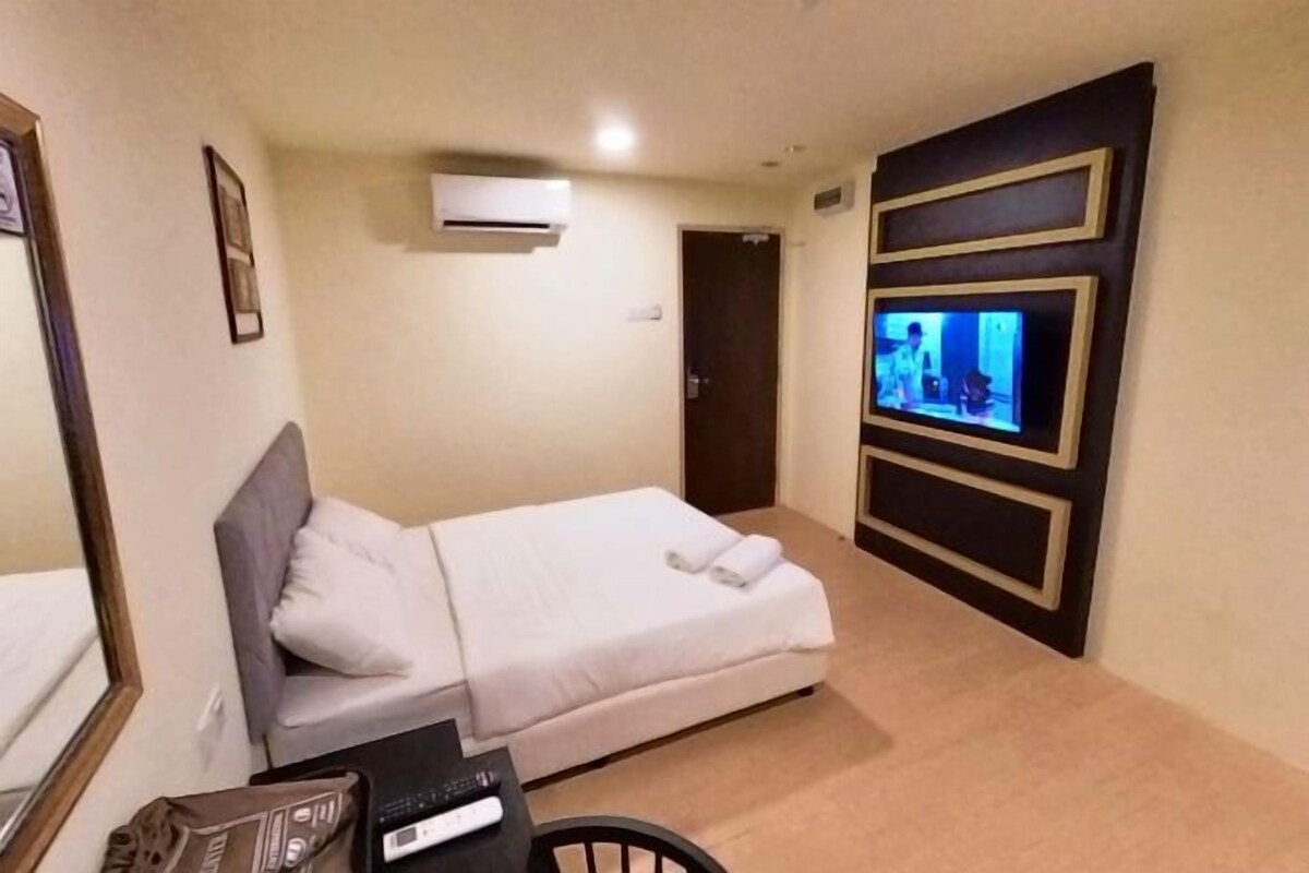 Une chambre d’hôtel équipée d’un lit, d’un téléviseur fixé au mur, d’un bureau avec une chaise et d’un appareil de climatisation.