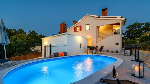Une maison moderne dotée d’une piscine, d’un espace salon extérieur et d’un escalier menant à un étage supérieur.