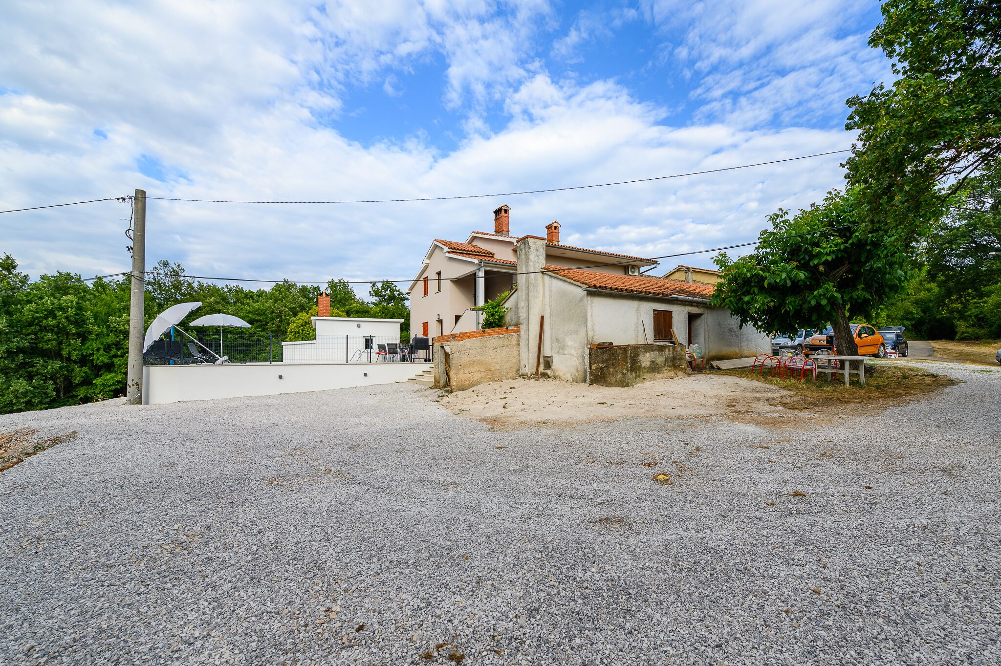 A two-story house with a gravel driveway and a small garden area.