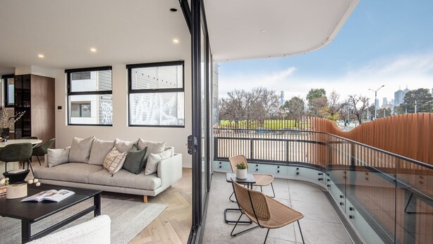 A modern living room with a sofa, coffee table, and chairs, a balcony with a railing, and a city view. - Pet Friendly - Sport Precinct Luxury Style over four levels (Cremorne)