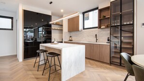 A modern kitchen with a marble island, wooden cabinets, and a built-in wine rack. - Pet Friendly - Sport Precinct Luxury Style over four levels (Cremorne)