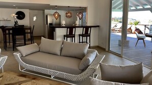 Una sala de estar moderna con sofá, comedor y vistas a una terraza.
