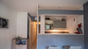 Una cucina compatta con forno a microonde, lavello e sgabelli da bar.