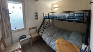 Camera con letto a castello, scrivania, sedia e finestra.