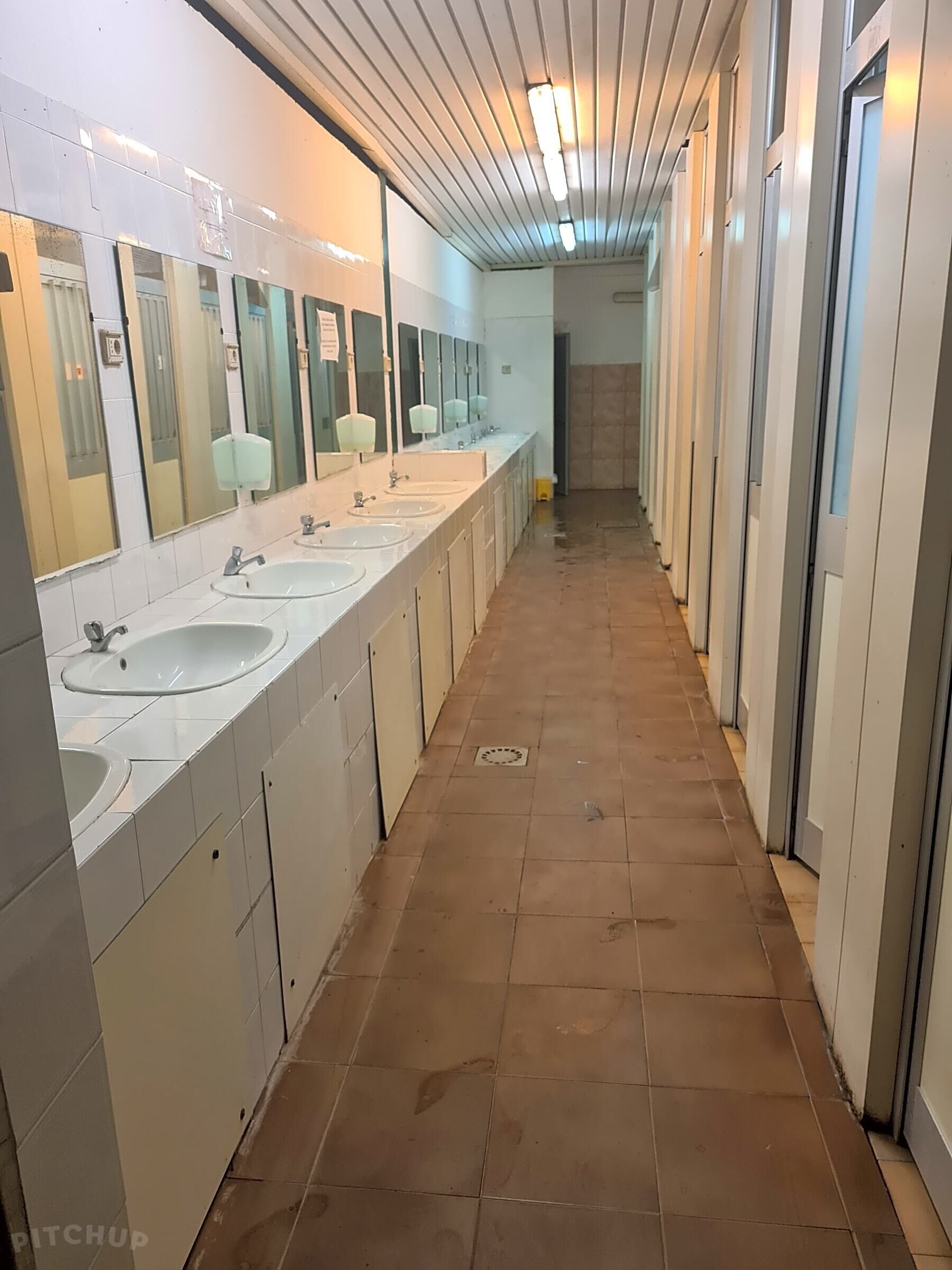 Un baño largo y estrecho con varios lavamanos y espejos.