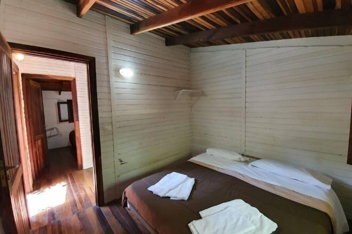 A small, single-bed room with wooden walls and a sloped ceiling.