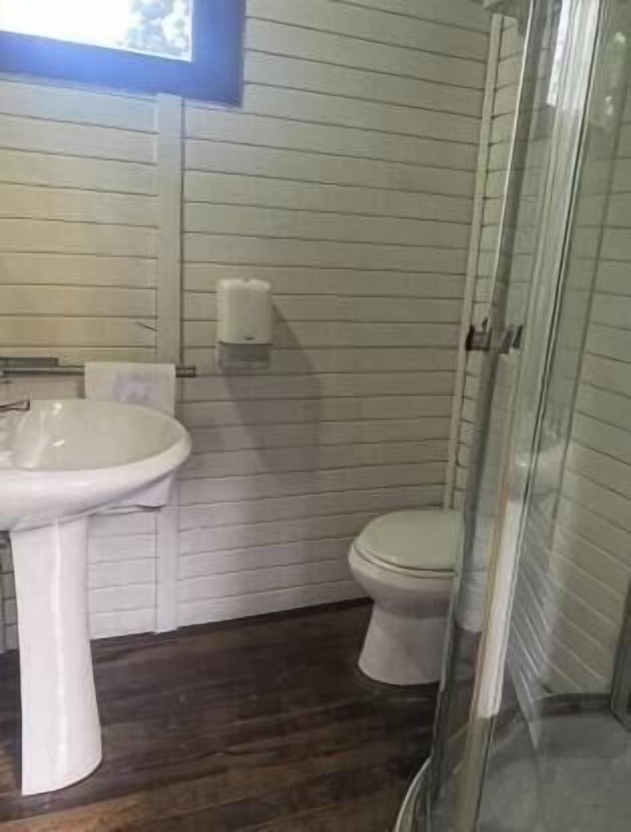 Un baño con lavamanos blanco, inodoro y cabina de ducha de vidrio.