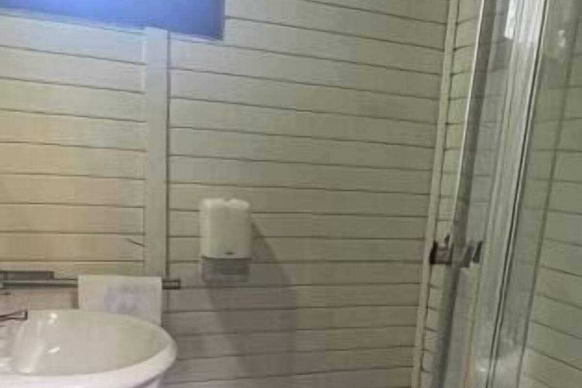 A bathroom with a white sink, toilet, and a glass shower enclosure.