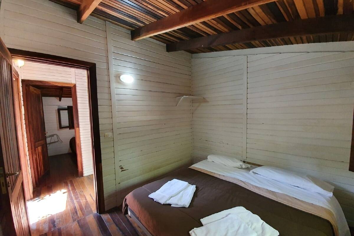 A small, single-bed room with wooden walls and a sloped ceiling.