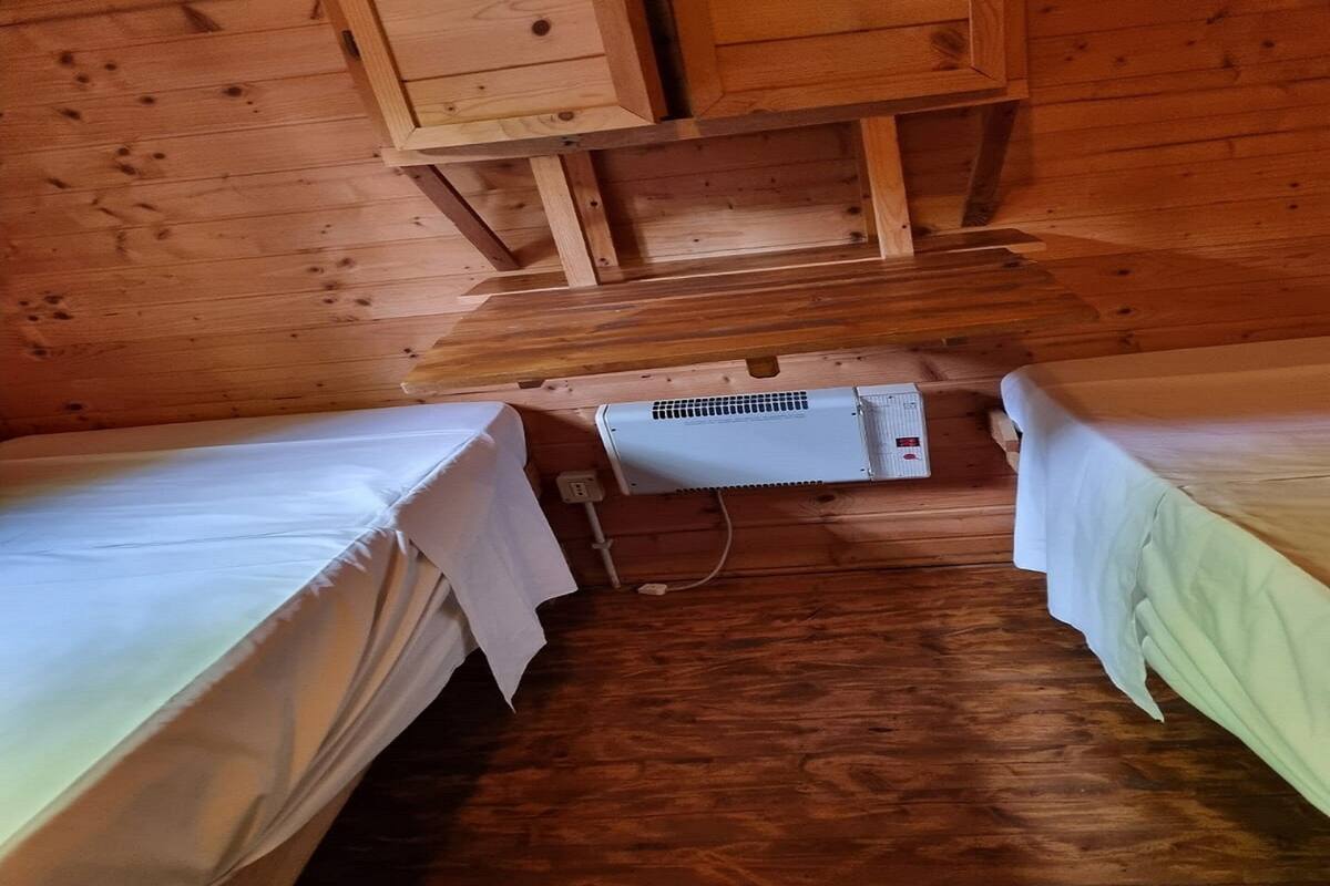 A cabin with two single beds, a wooden ceiling, and a wall-mounted air conditioning unit.