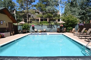 Une piscine rectangulaire dont le bord est recouvert de carrelage, entourée de chaises longues et de parasols.